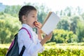 Schoolgirl eating an apple and reading a book on the way home through the park Royalty Free Stock Photo