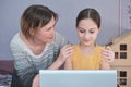 The schoolgirl is engaged in a laptop and mom encourages her daughter and holds her by the shoulders Royalty Free Stock Photo