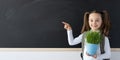 Schoolgirl girl with a briefcase near the school blackboard stands with a flower. Chalk board and place for text