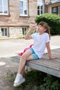 Schoolgirl girl drinks fresh mineral water from a bottle in the schoolyard. Take a break from school. Quenching thirst,