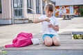 Schoolgirl girl drinks fresh mineral water from a bottle in the schoolyard. Take a break from school. Quenching thirst, Royalty Free Stock Photo