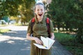 a schoolgirl girl is yawning, she is tired of reading a boring book, a city street on a bright summer day Royalty Free Stock Photo