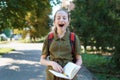 a schoolgirl girl is yawning, she is tired of reading a boring book, a city street on a bright summer day Royalty Free Stock Photo