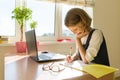 Schoolgirl, girl of 8 years, sitting at table with books and writing in notebook. School, education, knowledge and children. Royalty Free Stock Photo