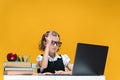 Schoolgirl in glasses raising hand sitting at laptop during online lesson. Distant School Learning. Royalty Free Stock Photo