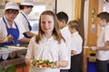Schoolgirl holding a plate of food in a school cafeteria
