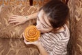 A schoolgirl at home on the sofa bites a sweet bun