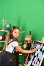 Schoolgirl with interested face stands by school stationery