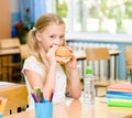 Schoolgirl looking at camera while having lunch during break Royalty Free Stock Photo