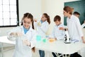 Schoolgirl making experiment with teacher and pupils in class Royalty Free Stock Photo