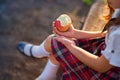 Schoolgirl in uniform is eating an apple in the park. Royalty Free Stock Photo