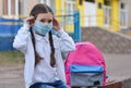 The schoolgirl puts on a mask to prevent colds and viruses. Medical concept.Back to school. Child going school after pandemic over Royalty Free Stock Photo