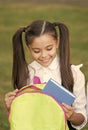 Schoolgirl putting book inside backpack, ready for lessons concept