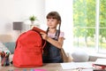 Schoolgirl putting stationery into backpack