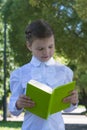 Schoolgirl reading book outside in park Royalty Free Stock Photo