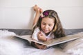 The schoolgirl is reading. Little girl reading a book in the bedroom on the bed. Education and hobbies of children Royalty Free Stock Photo