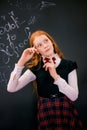 A schoolgirl with red long hair in a school uniform stands near school board Royalty Free Stock Photo