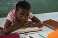 Schoolgirl relaxing on an open book in classroom