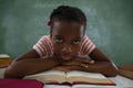 Schoolgirl relaxing on open book in classroom