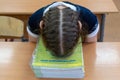 A schoolgirl in a school uniform lies on a desk with textbooks. Fatigue and congestion in school education in children