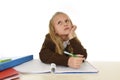 Schoolgirl in school uniform sitting at studying desk doing homework looking thoughtful and absent mind Royalty Free Stock Photo