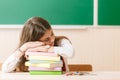 Schoolgirl in school uniform sleeps on the books at the school desk Royalty Free Stock Photo