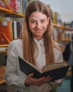 Schoolgirl searching and choosing books in the library