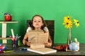 Schoolgirl sits at desk with colorful stationery, books and flowers