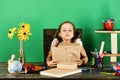 Schoolgirl sits at desk with colorful stationery, books and flowers