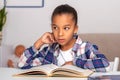 The schoolgirl siting at the table indoors and doing his homework Royalty Free Stock Photo