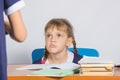Schoolgirl sitting at the desk angrily looks at another girl