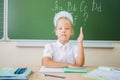 Schoolgirl sitting at desk, school classroom, on background of board Royalty Free Stock Photo