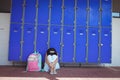 Schoolgirl sitting on pavement by lockers in corridor