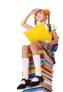 Schoolgirl sitting on pile of books.
