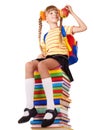 Schoolgirl sitting on pile of books.