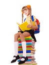 Schoolgirl sitting on pile of books.