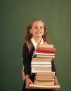 Schoolgirl with smiling face holds huge pile of books Royalty Free Stock Photo