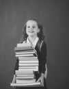 Schoolgirl with smiling face holds huge pile of books Royalty Free Stock Photo