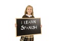 Schoolgirl smiling happy and cheerful holding and showing small blackboard with text I learn Spanish