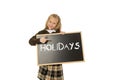 Schoolgirl smiling happy holding and showing blackboard with text holidays in end of school Royalty Free Stock Photo