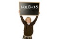 Schoolgirl smiling happy holding and showing blackboard with text holidays in end of school Royalty Free Stock Photo