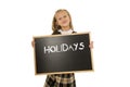 Schoolgirl smiling happy holding and showing blackboard with text holidays in end of school Royalty Free Stock Photo