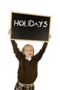 Schoolgirl smiling happy holding and showing blackboard with text holidays in end of school Royalty Free Stock Photo