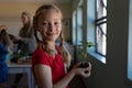 Schoolgirl standing holding a seedling plant in earth in an elementary school classroom Royalty Free Stock Photo