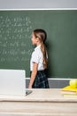 schoolgirl standing near chalkboard with equations