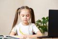 Schoolgirl studying homework during her online lesson at home, online education and online school concept, home schooler. Distance Royalty Free Stock Photo