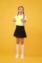 Schoolgirl studying textbook. Exciting literature. Girl child hold book stand yellow background. Kid girl school uniform