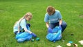 Schoolgirl and teacher putting plastic in garbage bag, social responsibility