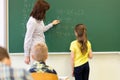 Schoolgirl and teacher with task on chalk board Royalty Free Stock Photo