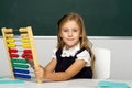 Schoolgirl in uniform practising math using abacus Royalty Free Stock Photo